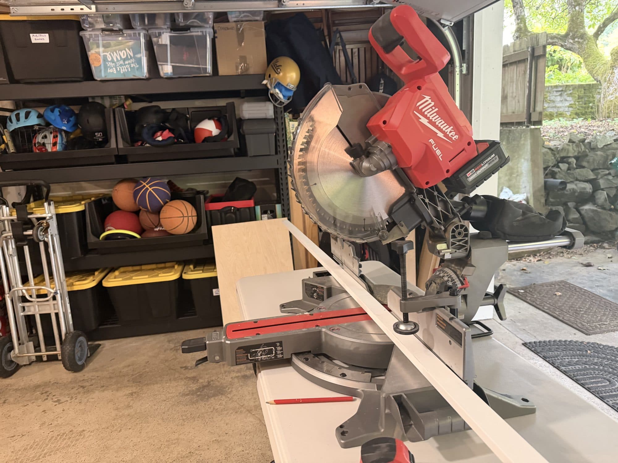 A miter saw set up in the garage, cutting a white board for the closet