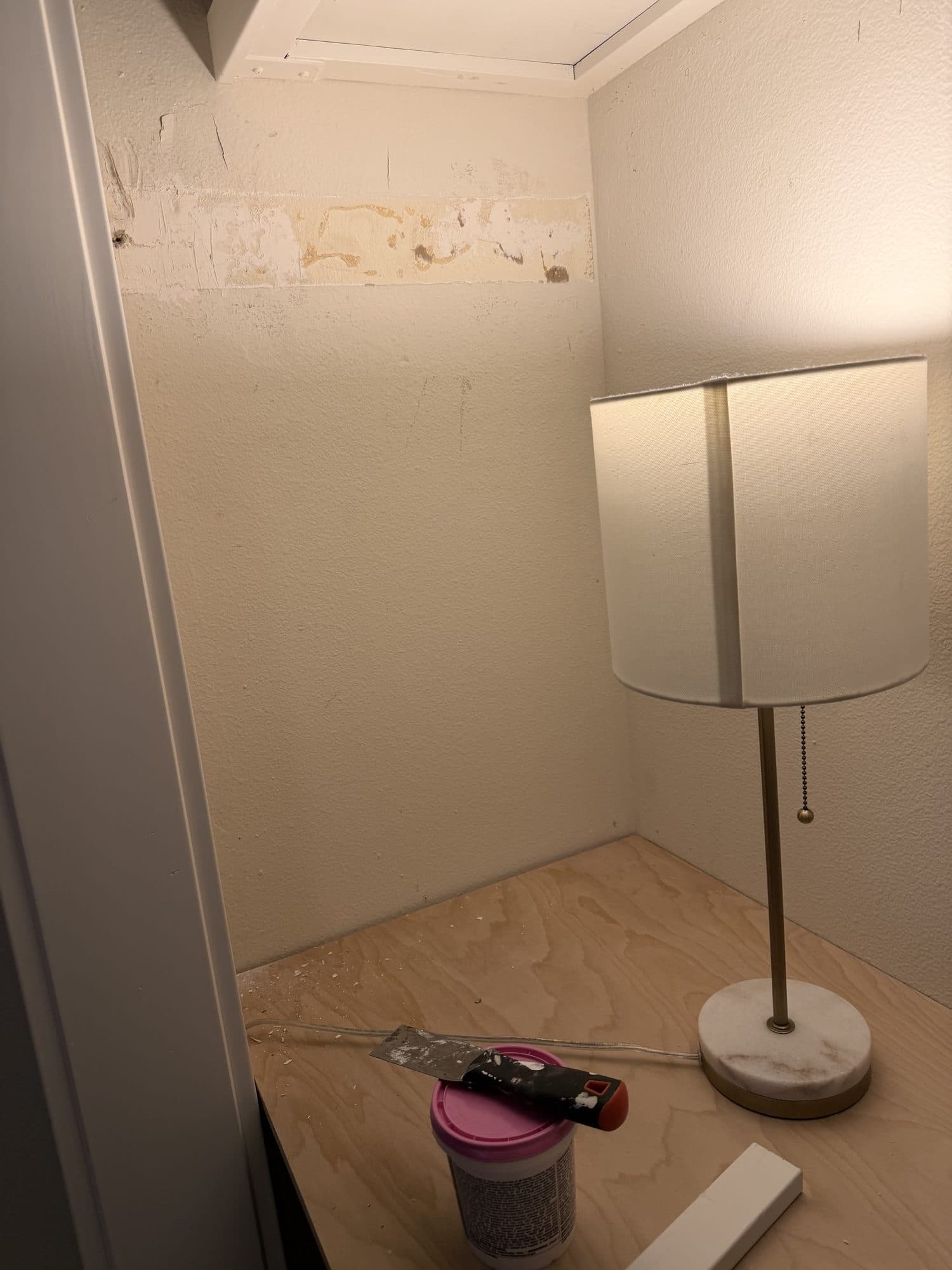 The back wall of the closet above the new desktop, lit by a lamp