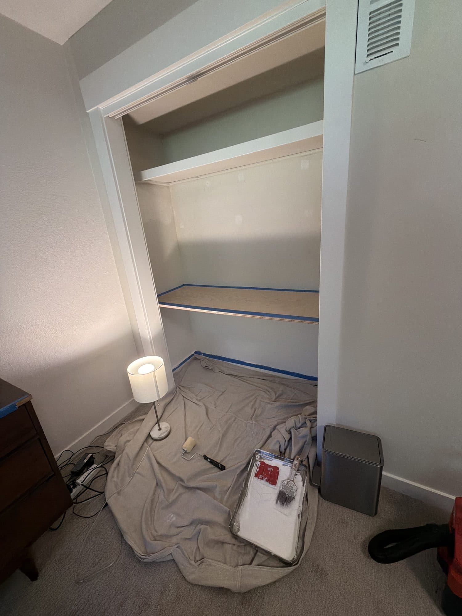 Drop cloths, a paint tray, and fresh paint in the closet