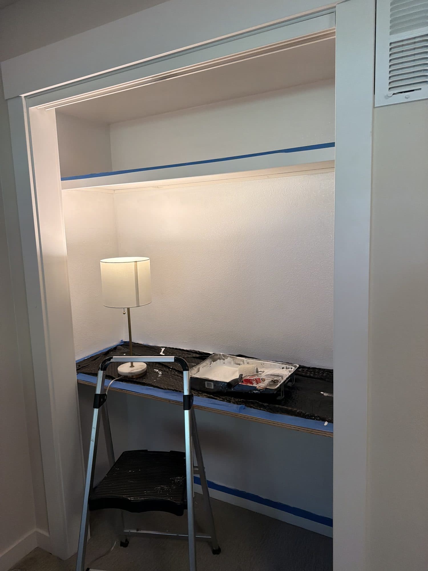 A step ladder and paint supplies on the desktop while the trim is painted