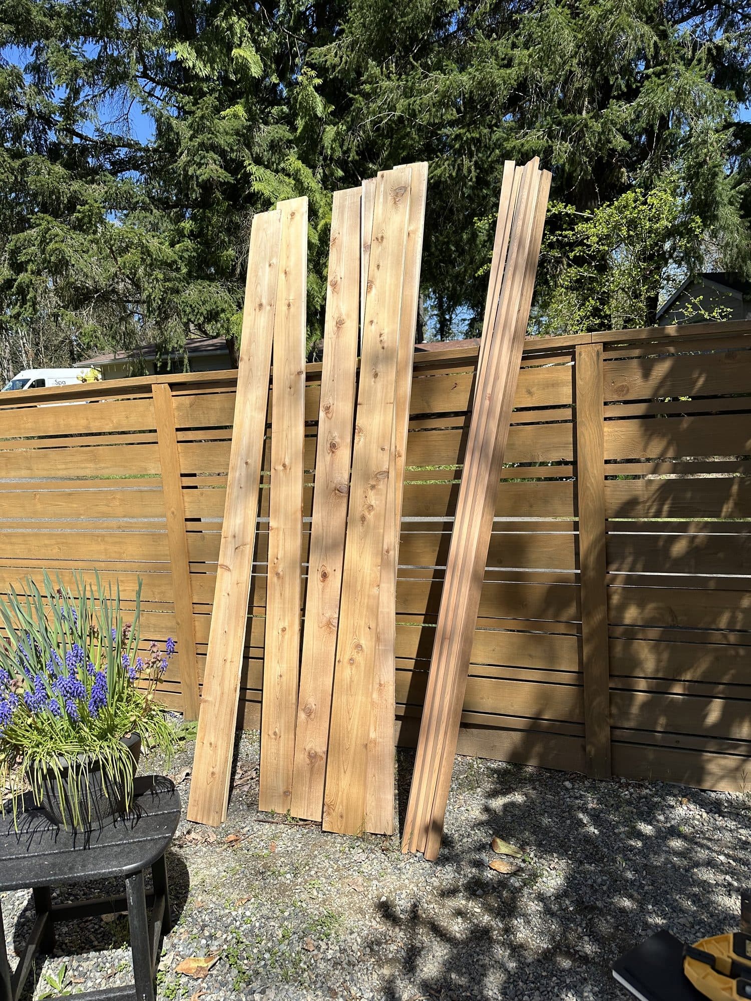 Fresh cedar boards leaning against the finished fence