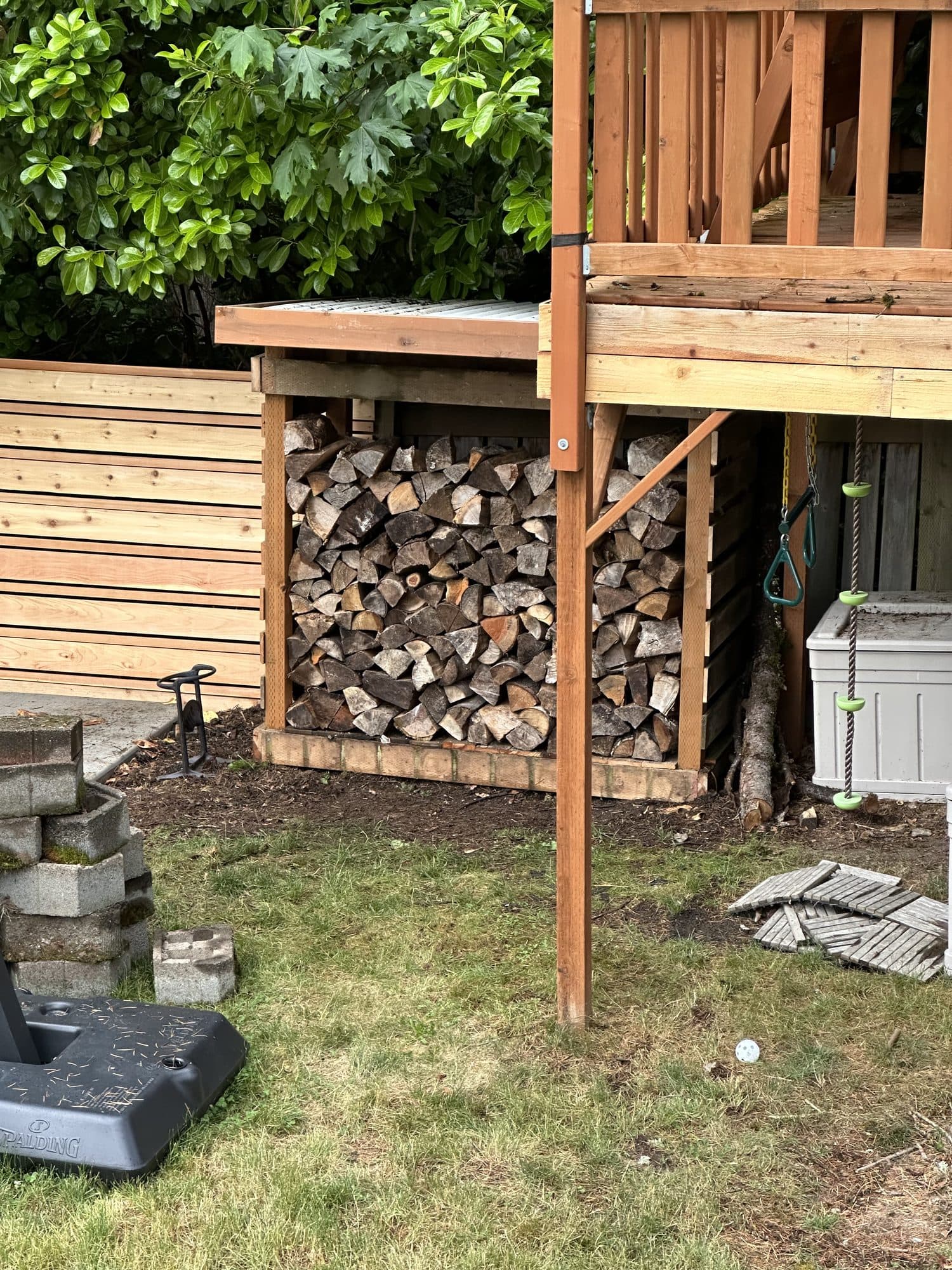 The wood shed stacked full of firewood beneath the tree house